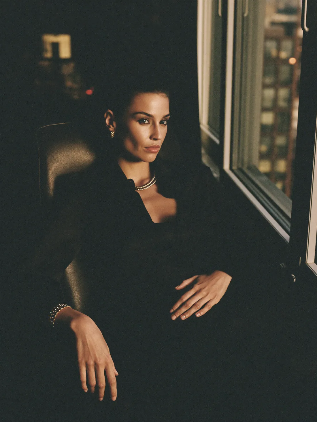Portrait of a creator seated beside a window at night